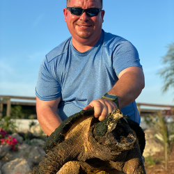 Bob Kerr, owner of Freedom Stone + Pondscapes, holding a giant tortoise