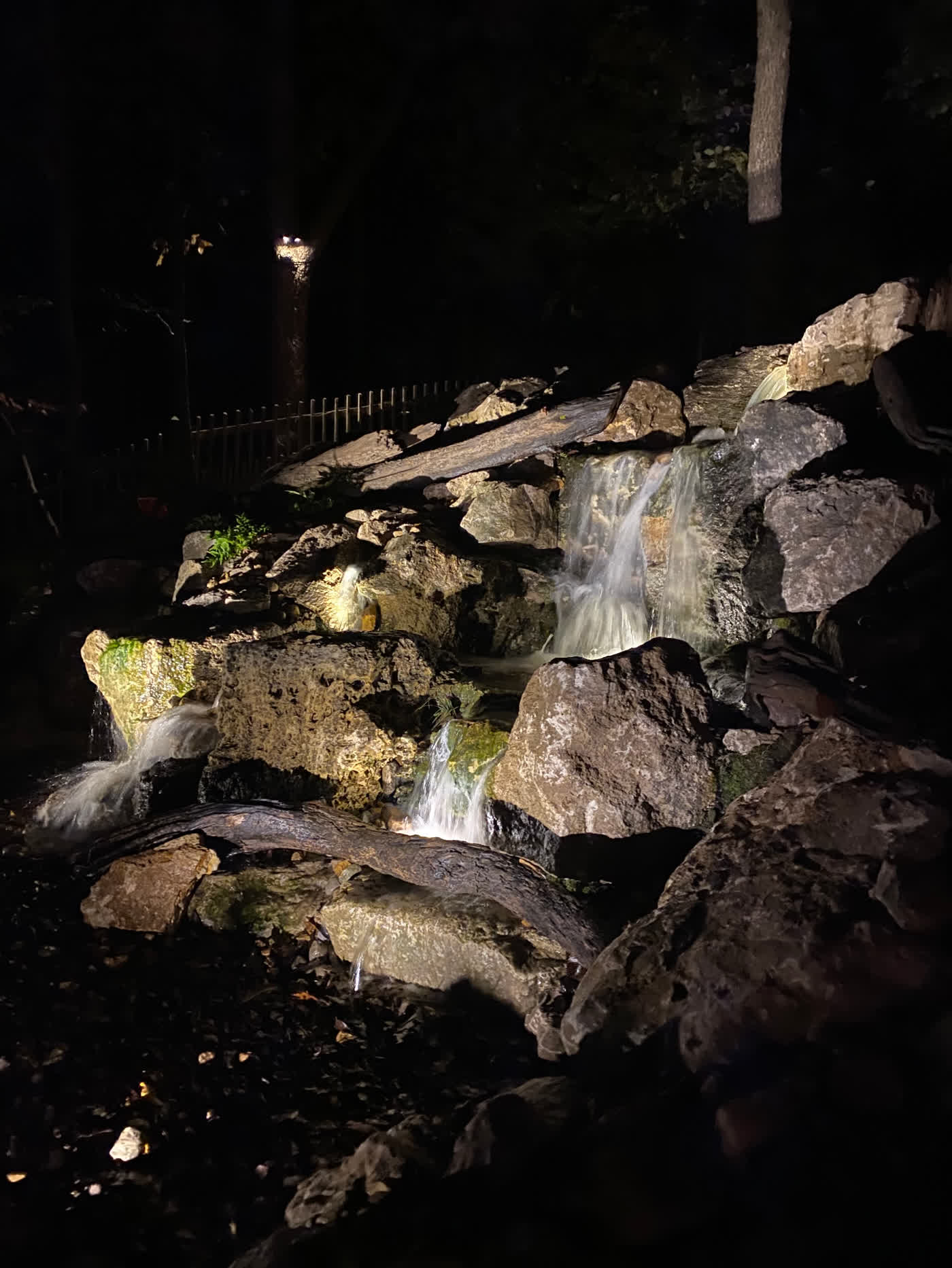 Illuminated waterfall cascading over natural stone at night