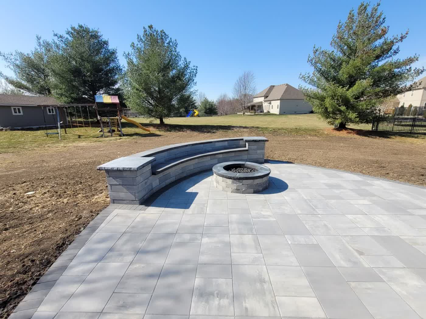 Expansive paver patio with curved seating wall and fire pit