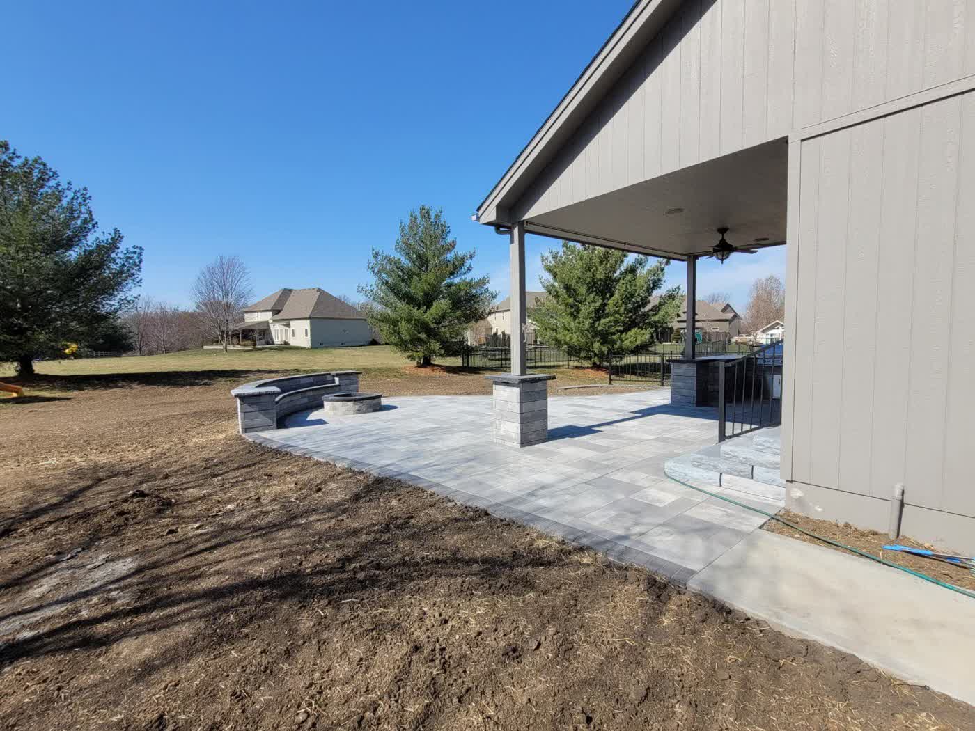 Paver patio with covered structure, fire pit, and stone columns