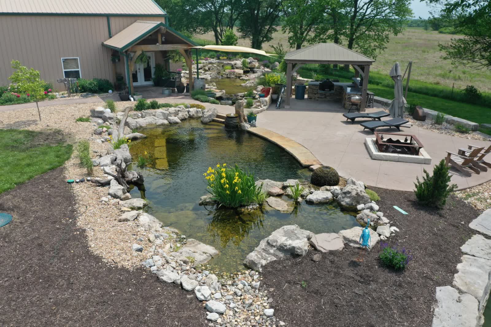 Intermediate swim pond with patio, outdoor kitchen, and fire pit
