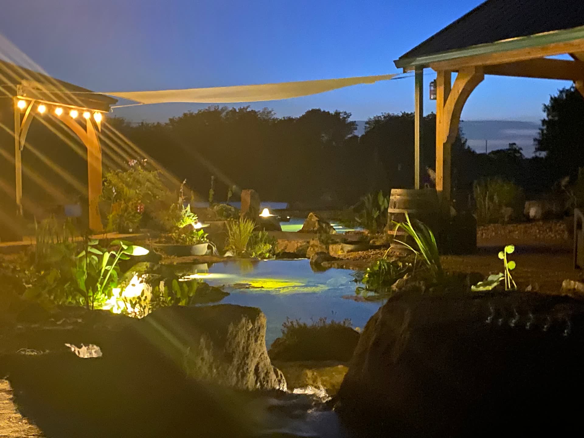 Swim pond with nighttime lighting and sail shades