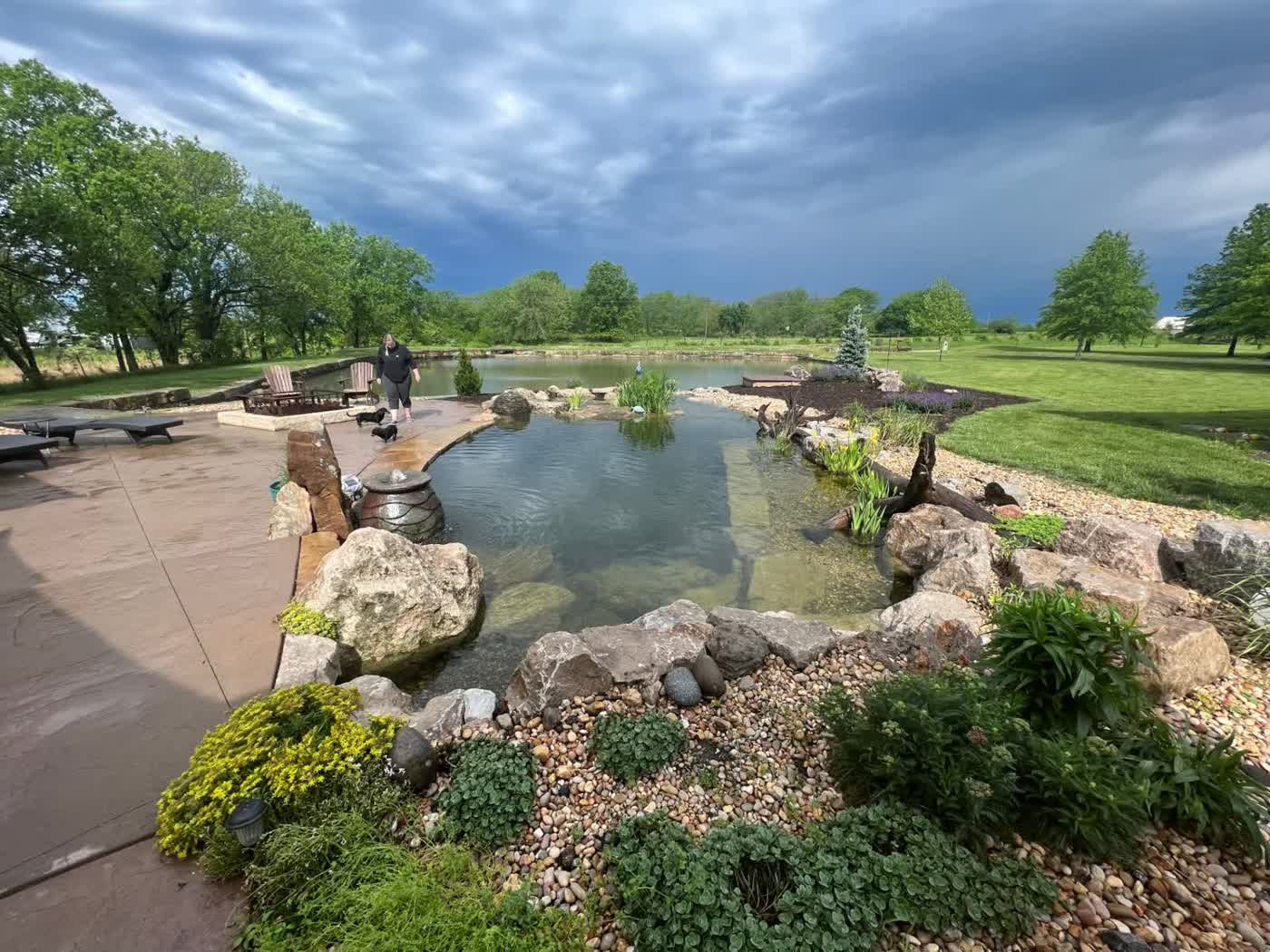 Large swim pond with patio and dramatic sky