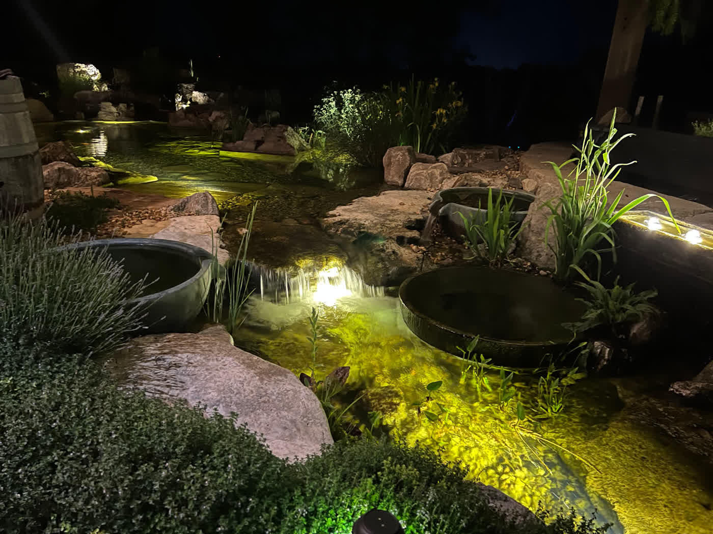 Nighttime swim pond with waterfall and planters