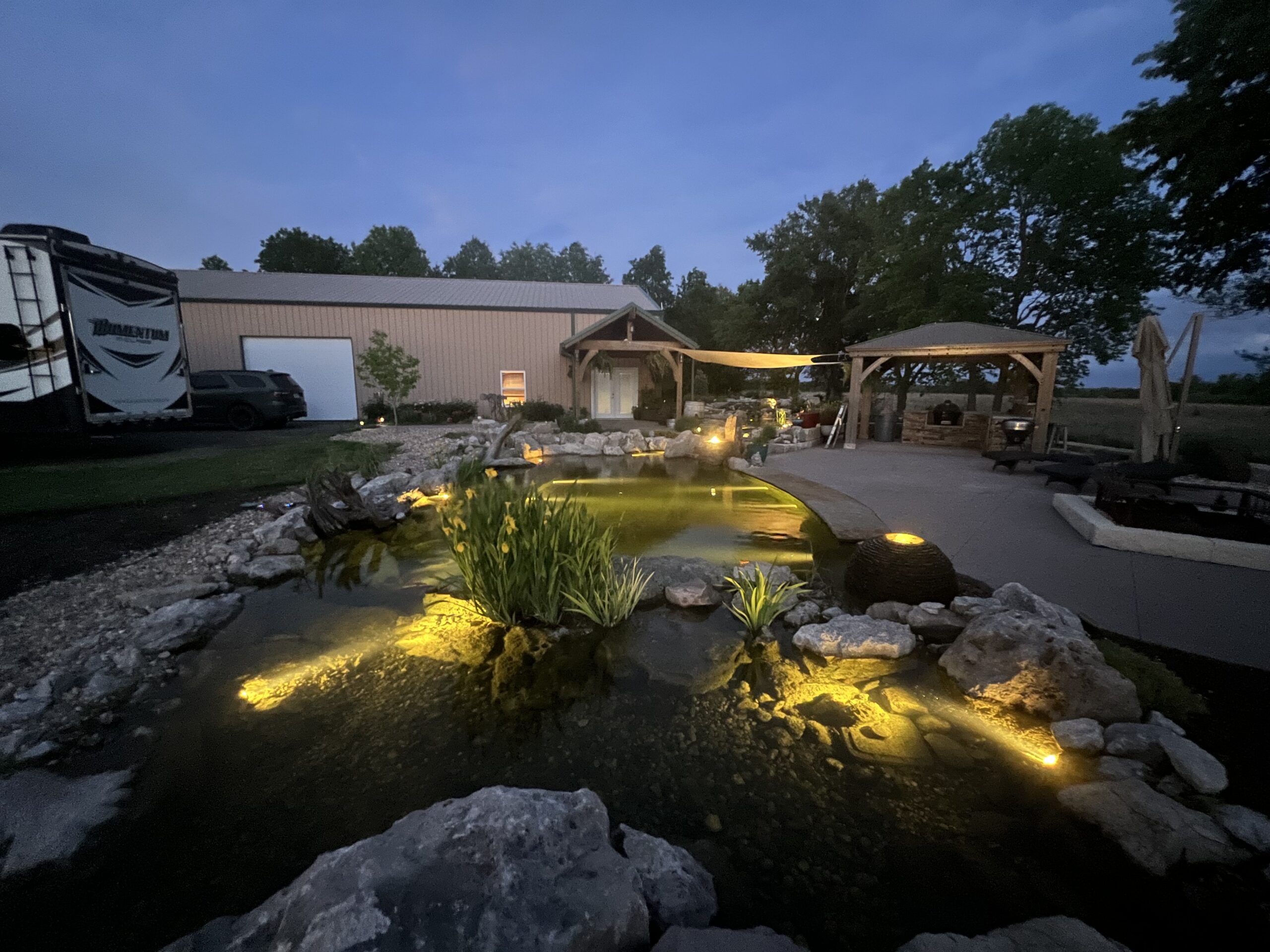 Koi pond with aquatic plants and waterfall feature in Bentonville backyard